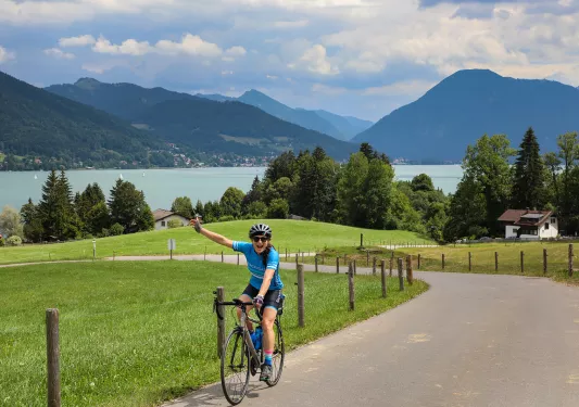 Biker riding on road with scenic German lake in background.