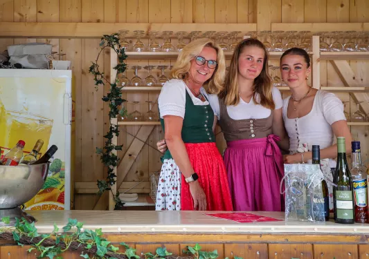 Three women posing together in traditional German dresses.