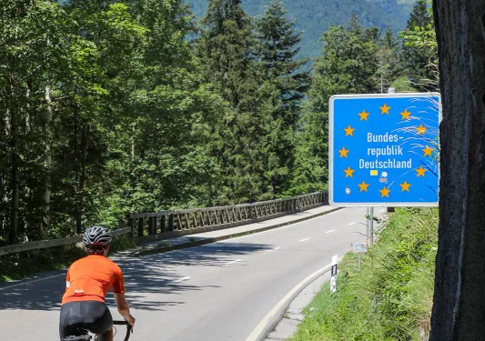 Biker riding past sign that reads "Bundes-republik Deutschland"