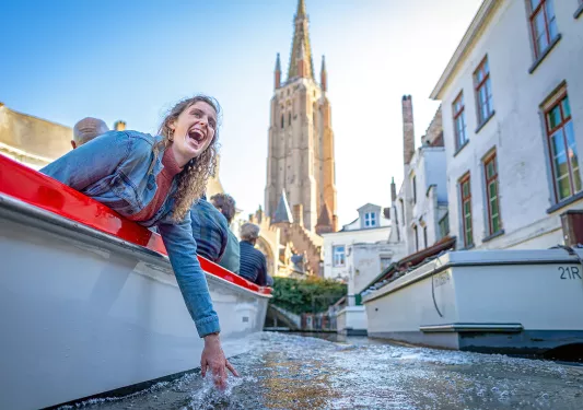 Guest dipping hand in water on boat