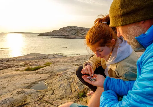 Father and daughter looking at seashells on a beach