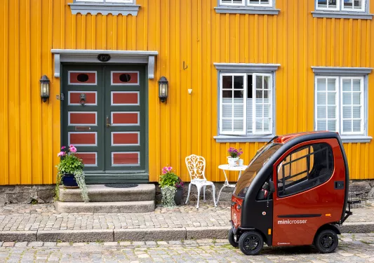 Tiny smart car parked in front of a building with bright yellow walls