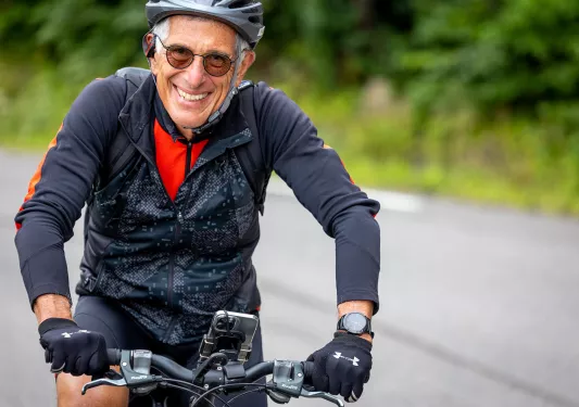 Older biker smiling while riding.