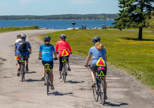 Five guests riding along a coastal trail, ocean to their left.