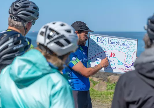 Guests receiving D5 leader brief, ocean in background.