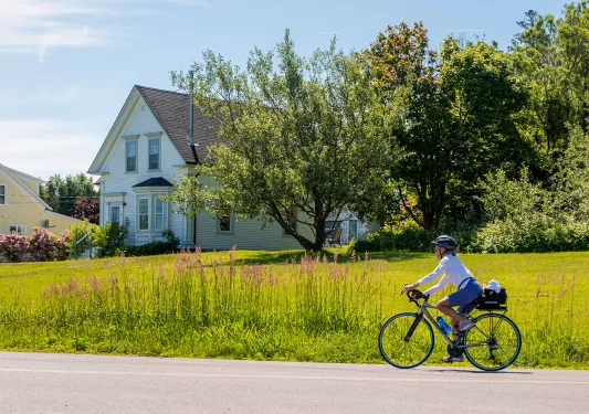 Guest cycling in front of farmhouse and field.