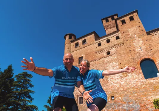 Two guests posing for camera, large brick building behind them.