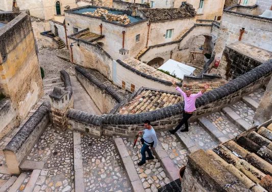 Two guests walking down stone and brick stairs, houses and buildings behind them.