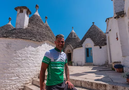 Guest smiling in front of Alberobello houses.