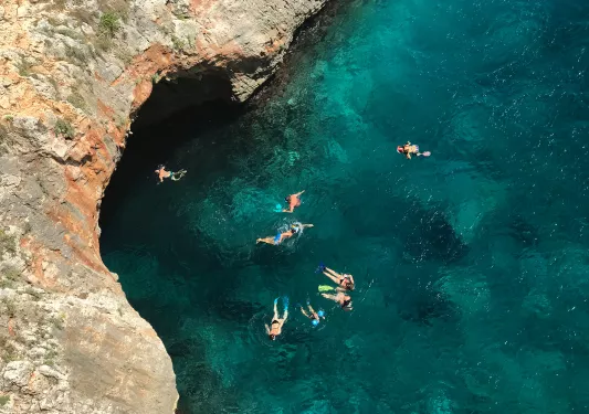 People swimming in a clear blue body of water, Portugal.