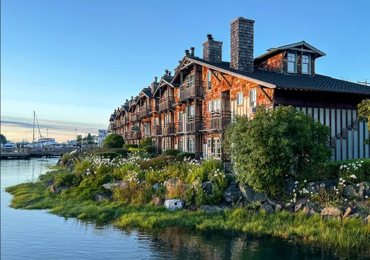Row of wood-plated houses along the coast, pier in background.