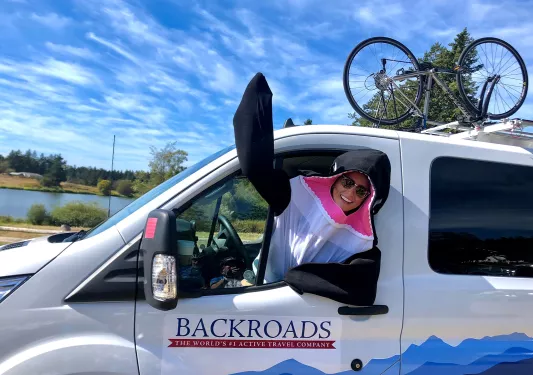 Leader in orca costume waving to camera in the front seat of BR van.