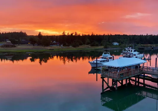 Shot of two ships at pier, sun setting in background.