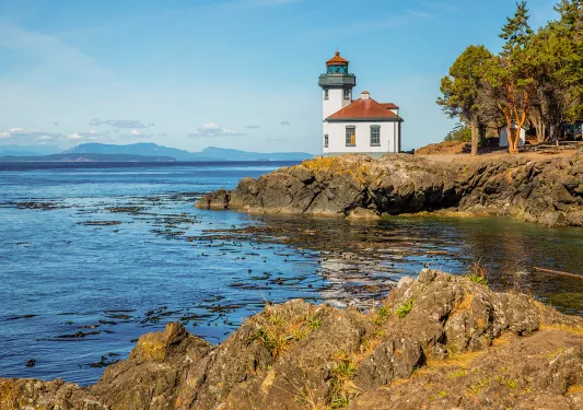 Coastal shot of a small lighthouse on a rocky shore.