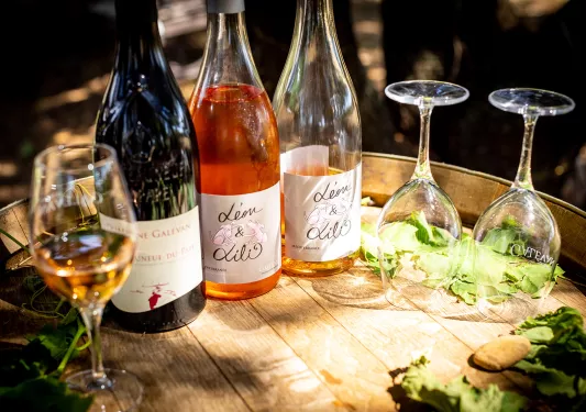 Close-up of wine glasses, bottles on barrel.