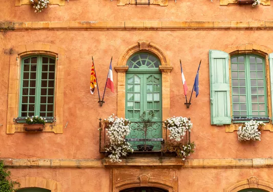 Shot of orange building, flags, balcony, windows, wood door.