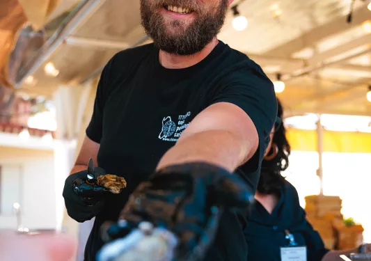 POV shot of local handing guest an oyster.