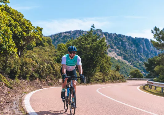 Guest cycling down road, forested hills behind them.