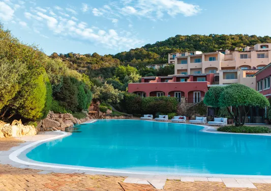 Shot of hotel pool, colorful rooms, balconies behind.