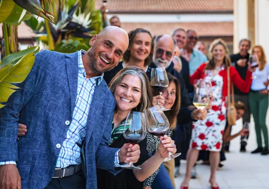 Group of guests, all looking towards camera, wine glasses in hand.