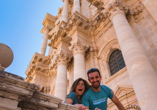 People smiling down from outside a church in Sicily