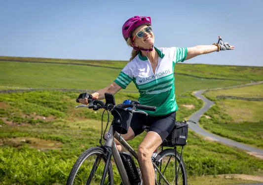 Guest on bike gesturing to meadow behind her.