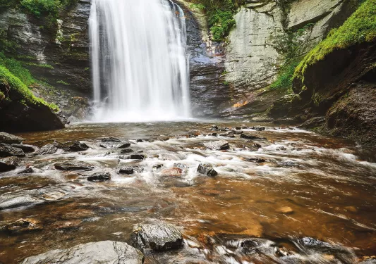 Shot of waterfall flowing into rocky stream.