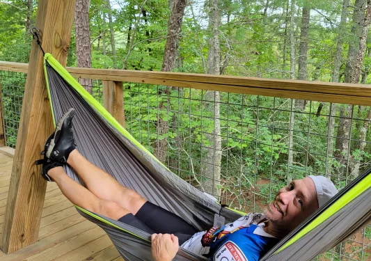 Guest relaxing in hammock among forest.