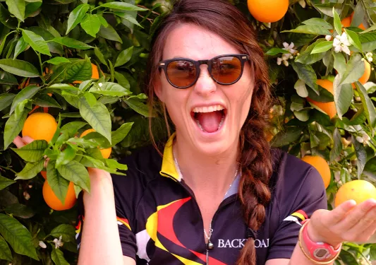 Guest/leader under an orange tree, smiling at camera.