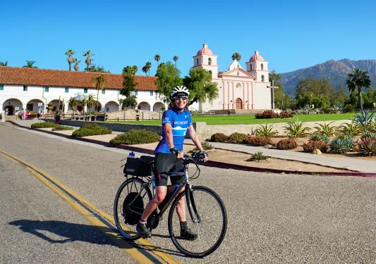 Guest posing on bike in front of cathedral/church.
