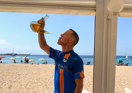 Biker drinking from carafe on the beach.