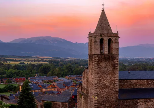 Shot of Spanish village during sunset, large church clock-tower at center.