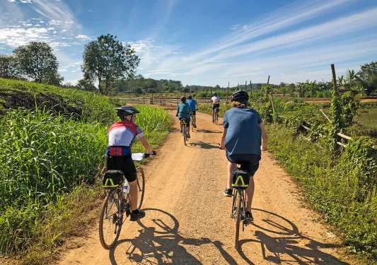 Backroads guests riding along a dirt path in Thailand
