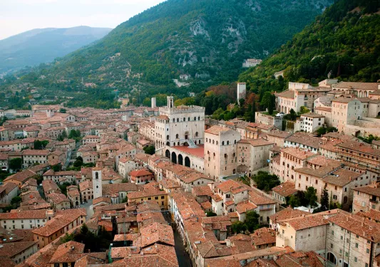 Wide shot of Italian town in valley, terracotta roofing, sandstone brick. 