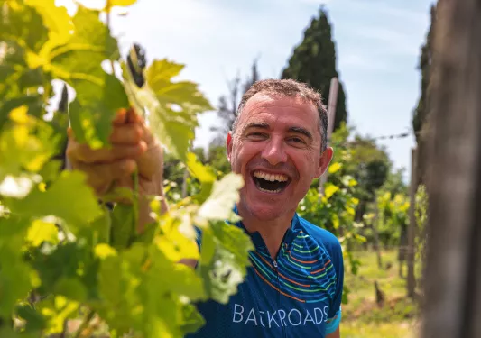 Guest laughing while inspecting grape-vine. 