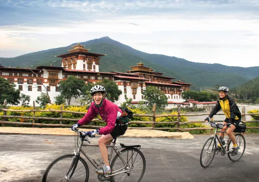 Two bikers riding beside a temple in Bhutan