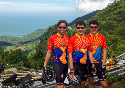 Three guests in bike gear, large forest vista behind them.