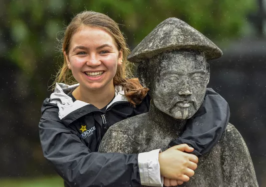 Woman posing with an old stone statue in Vietnam