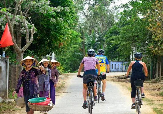 Guests cycling down road, past locals.