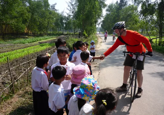 Backroads biker stopping to talk to children in Vietnam