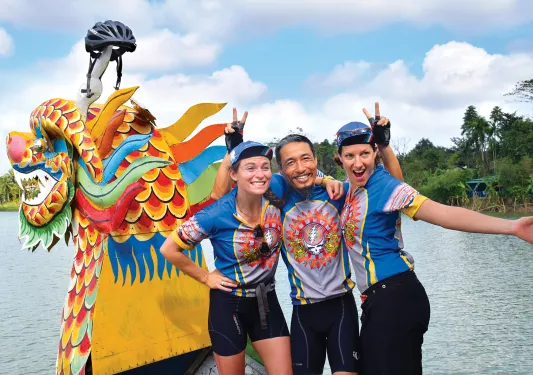 Three Backroads leaders laughing and posing in front of a dragon boat