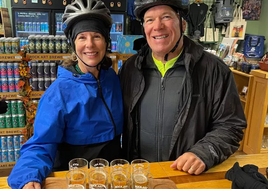 Two guests in store, posing with beer flight.
