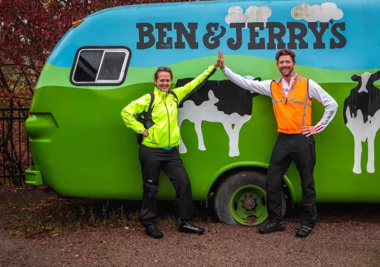 Two guests high-fiving in front of Ben & Jerry's car.