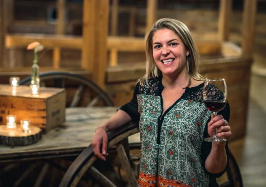 Guest leaning on wagon wheel, wine glass in hand.
