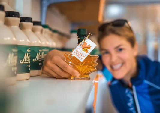 Guest holding maple syrup bottle to camera.