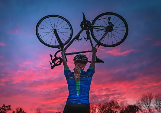 Backroads guest hoisting up bike during sunset