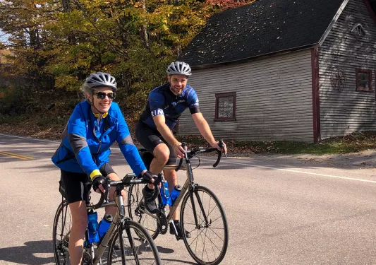 Two guests cycling past small shack.