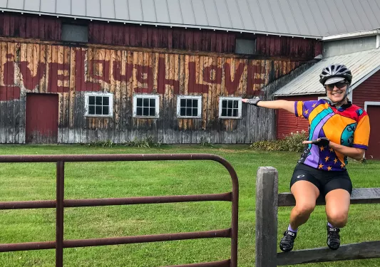 Guest sitting on fence, gesturing to "Live, Laugh, Love" painting.