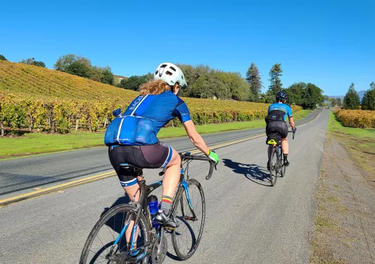 Two guests cycling amidst California vineyards.