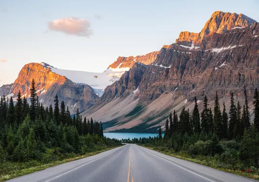 Wide shot of forest road, Large mountain range and river in distance.